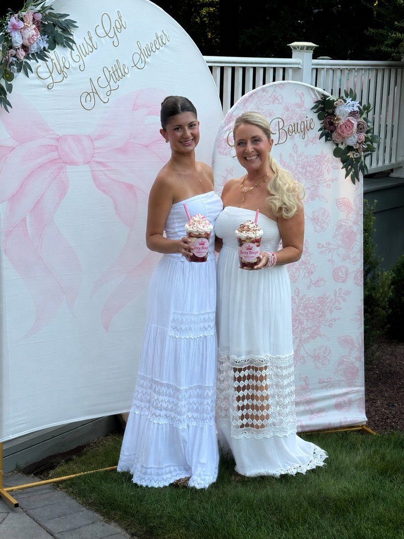 Berry Bougie mother-daughter founders holding strawberry cups at the launch event backdrop