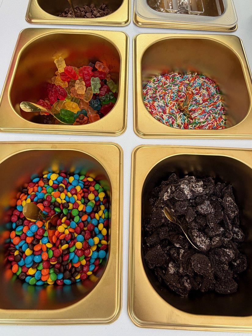 Close-up of Berry Bougie topping bar with gummy bears, sprinkles, M&M's, and crushed Oreos
