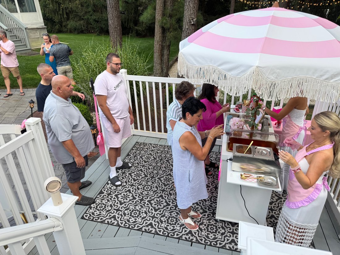 Guests lined up at the Berry Bougie cart under the pink striped umbrella